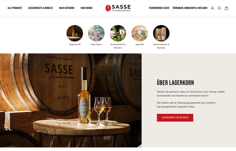 Flasche und Gläser auf Tisch vor Holzfässern, Text: "Über Lagerkorn".