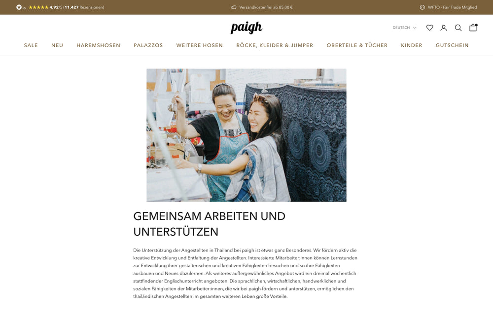 Zwei Frauen arbeiten zusammen an einer Nähmaschine mit blauem Stoff im Hintergrund.