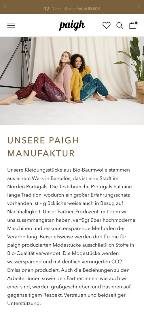 Zwei Frauen sitzen auf dem Boden in bunten Haremshosen, lächeln und posieren auf einem Teppich.
