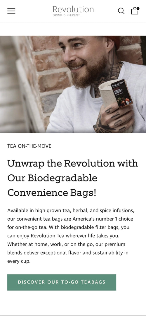 Mann in grauem Pullover hält Revolution-Tee und lächelt zur Seite.