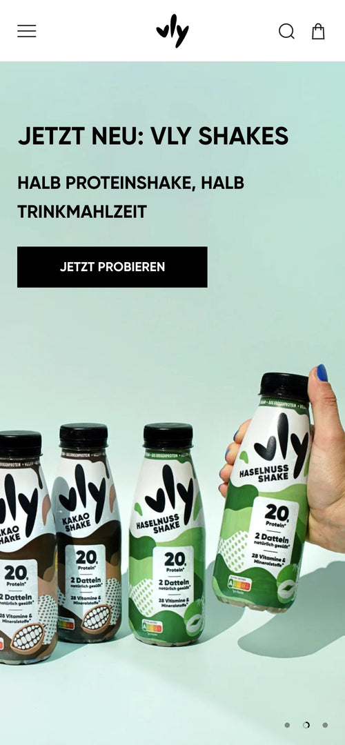 Drei Vly Shakes auf einem Tisch, Hand hält eine Flasche hoch.